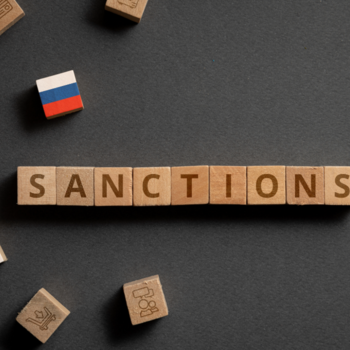 Das Wort Sanctions geschrieben mit Holzbuchstaben und eine russische Fahne aus Holzbausteinen.